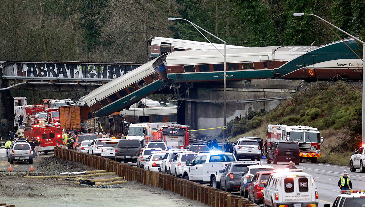 Cars from an Amtrak train lay spilled onto I-5 below as some remain on the tracks above in DuPont on Dec. 18, 2017. The National Transportation Safety Board has published its final report Monday , with the agencys vice chairman blasting what he described as a Titanic-like complacency among those charged with ensuring train operations are safe. The train was on its first paid passenger run on a new route from Tacoma to Portland, Oregon, when it plunged onto Interstate 5, killing three people and injuring dozens. (AP Photo/Elaine Thompson, file)