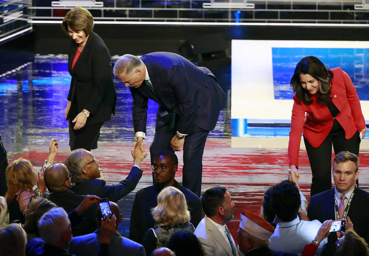 Democratic presidential candidates Sen. Amy Klobuchar, D-Minn. (left), Washington Gov. Jay Inslee and Rep. Tulsi Gabbard, D-Hawaii, greet supporters at the end of a Democratic primary debate hosted by NBC News at the Adrienne Arsht Center for the Performing Arts on Thursday in Miami. (AP Photo/Wilfredo Lee)