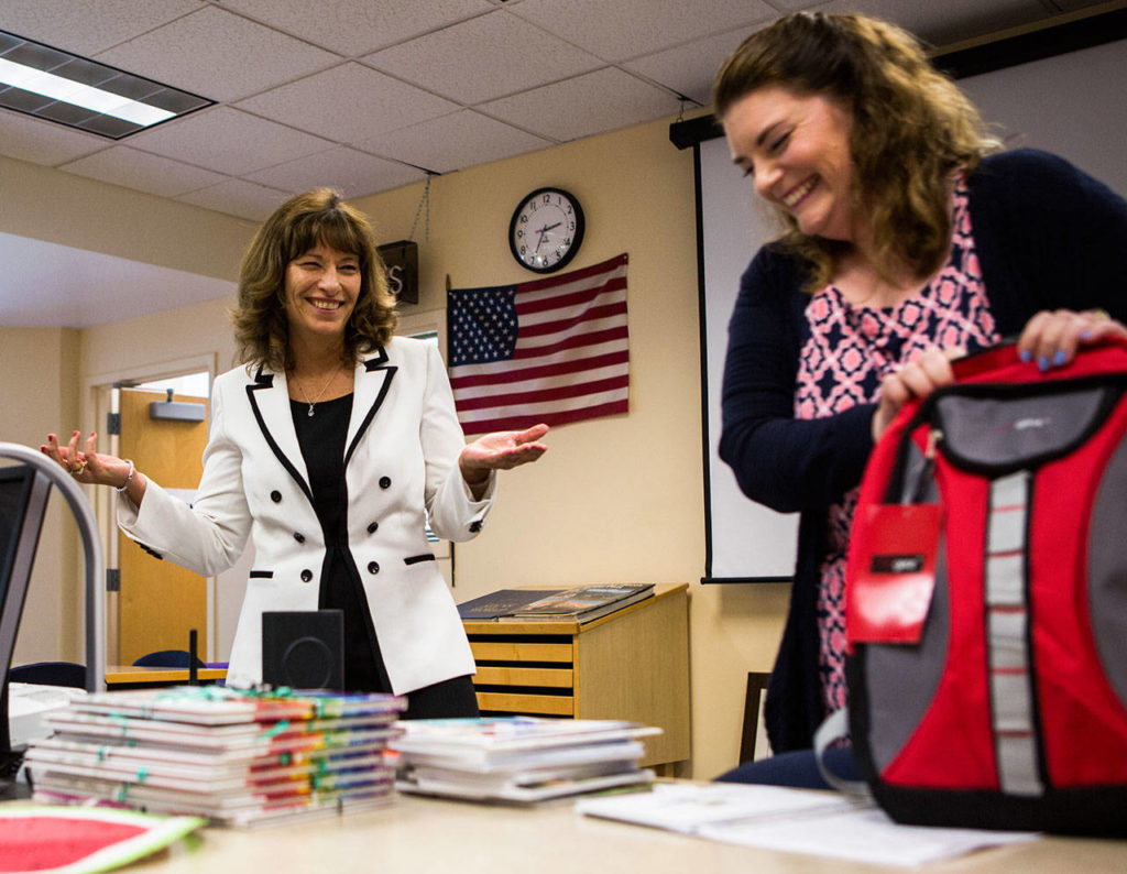 Alysia White (right) a seventh- and eighth-grade English teacher laughs as Joyce Stewart reacts to her goodbye gift in June at Evergreen Middle School in Everett. Stewart worked for the Everett School District for 20 years, including 12 years as a principal and eight more at the district administration office. She retires Wednesday. (Olivia Vanni / The Herald)
