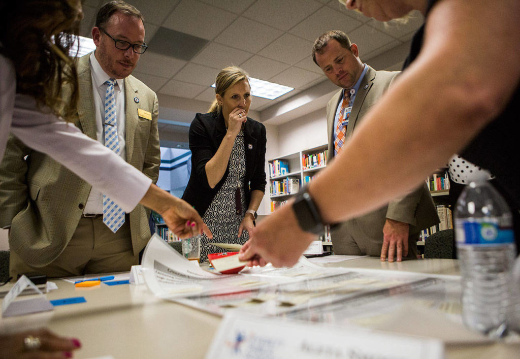 Cascade High School assistant principal Matt Bennett (left), Garfield Elementary principal Kathy Stilwell (center) and Director of Mathematics Michael McCarthy (right) work together on a component match game during one of the school tour stops. (Olivia Vanni / The Herald)
