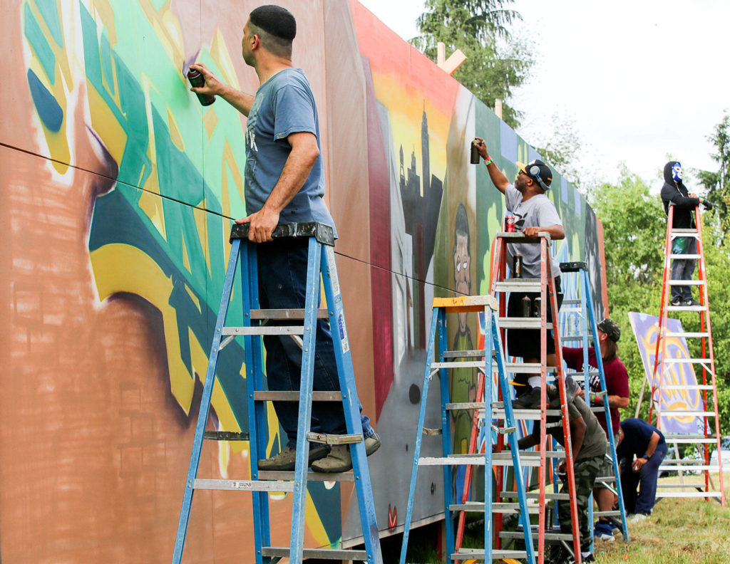 Members of Under the Influence paint a mural on July 4 near Snohomish. (Kevin Clark / The Herald)
