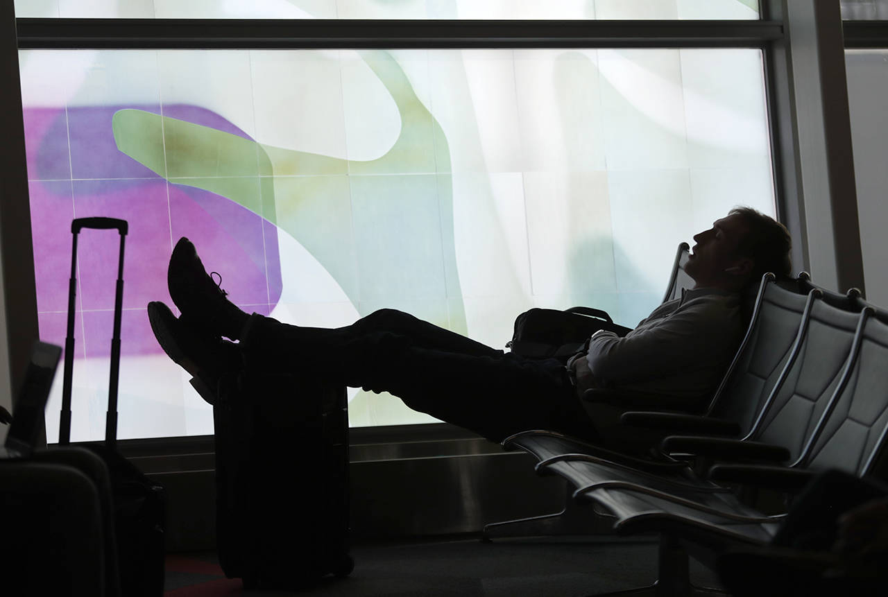 A traveler naps at he waits for his flight at Indianapolis International Airport in Indianapolis in 2018. (AP Photo/Michael Conroy, file)