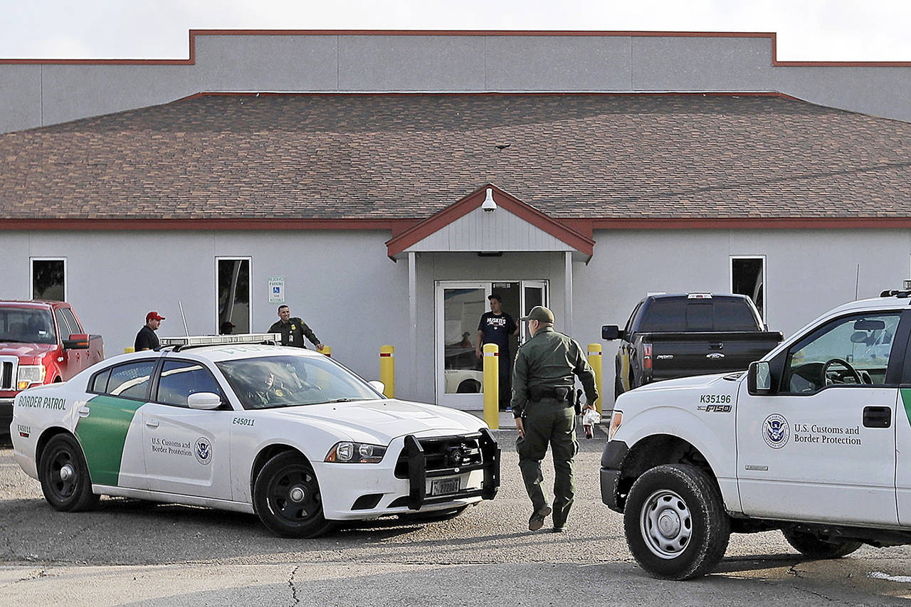In this June 2018 photo, a U.S. Border Patrol Agent walks between vehicles outside the Central Processing Center in McAllen, Texas. A report released Tuesday, July 2, 2019, by the Department of Homeland Security’s Office of Inspector General warns that facilities in South Texas’ Rio Grande Valley, including the CPC in McAllen, face “serious overcrowding” and require “immediate attention.” (AP Photo/David J. Phillip, File)