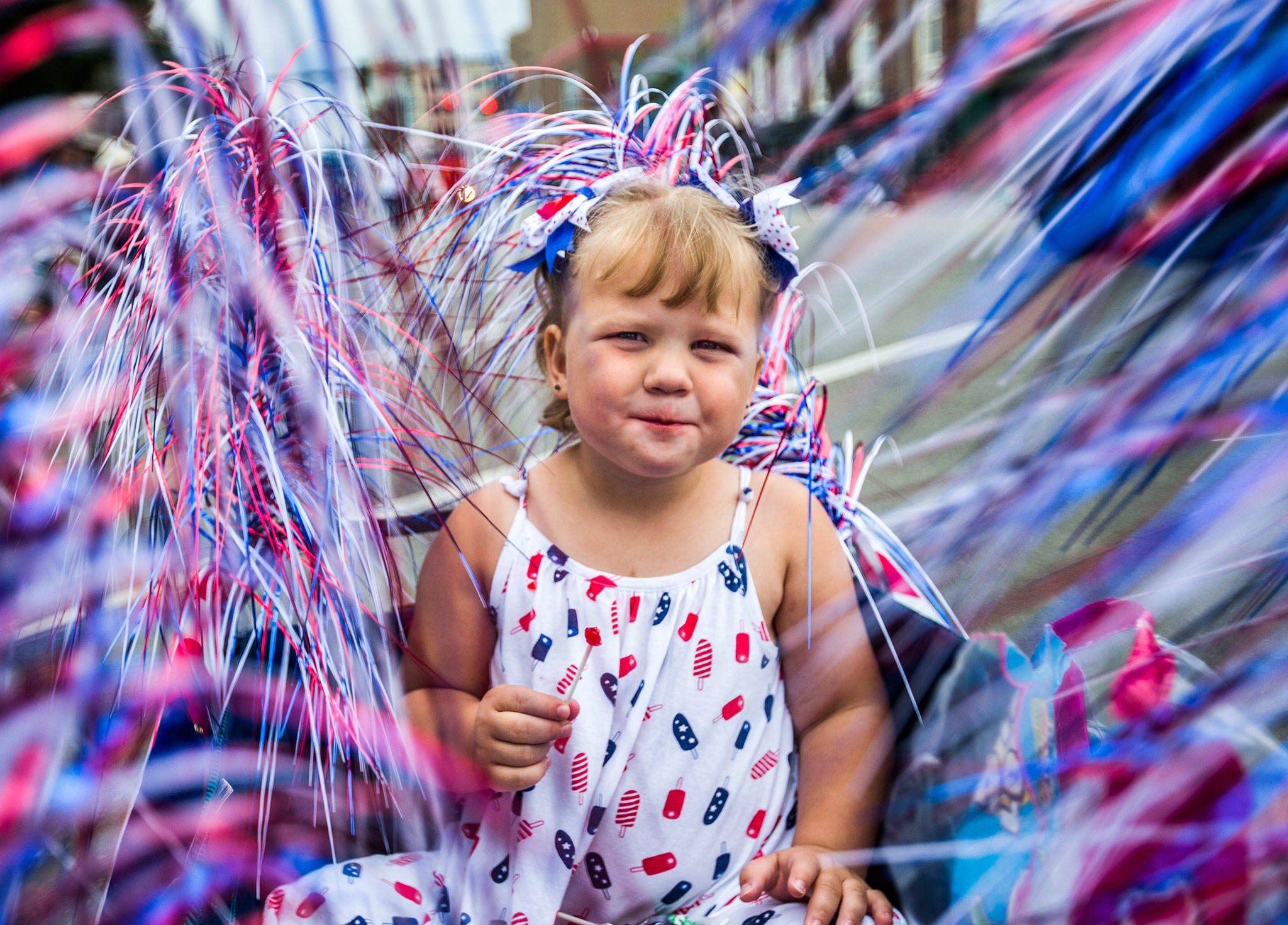 Makena Kombol, 2, rides in a wagon and hands out candy during the Colors of Freedom Fourth of July Parade on Thursday in Everett. Makena has been participating since she was 2 months old. (Olivia Vanni / The Herald)