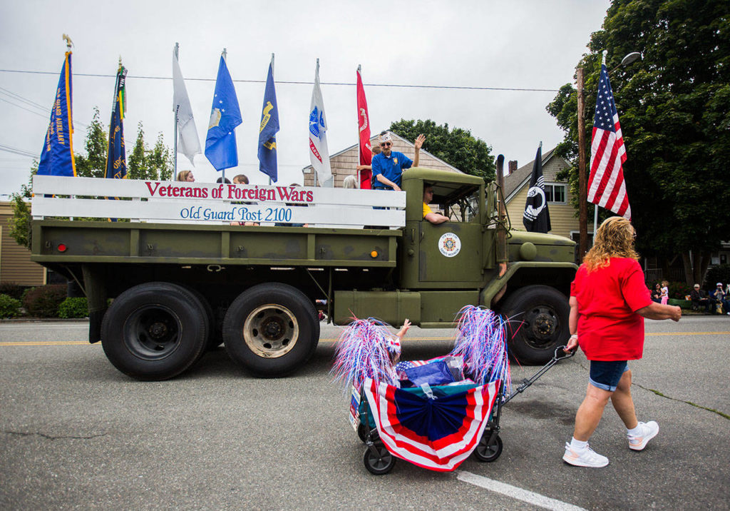 Members of the Veterans of Foreign Wars float wave at Makena Kombol as she passes by in her wagon during the Colors of Freedom Fourth of July Parade on Thursday. (Olivia Vanni / The Herald)
