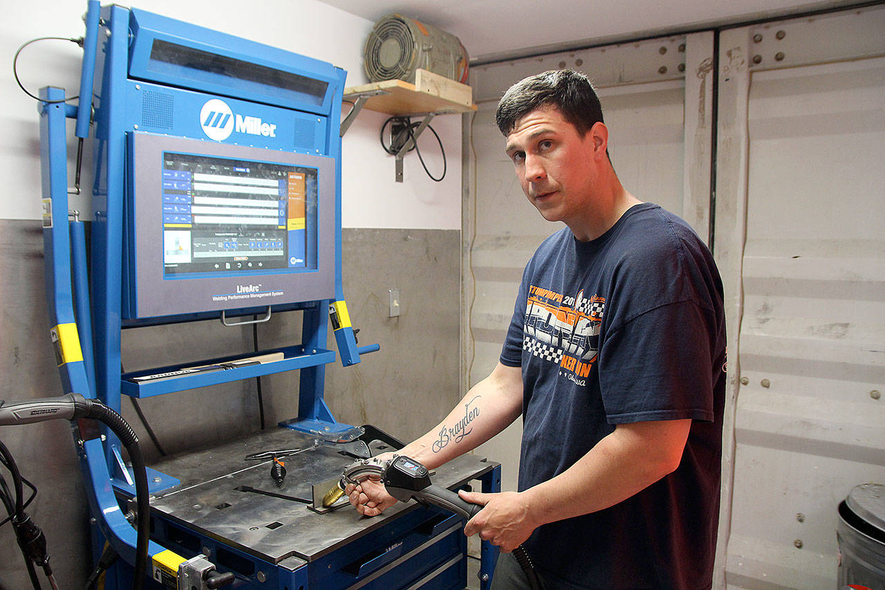 Joe Hilton, a welding instructor for the apprenticeship program, shows the machine that combines virtual reality with reality to teach welding skills. (Jessie Stensland / Whidbey News Group)