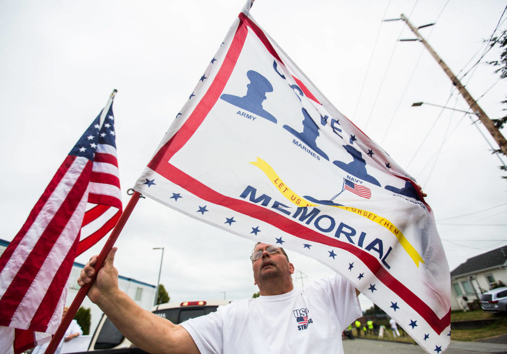 A member of the U.S. Veterans Memorial float group begins taking down their flag after the Colors of Freedom Fourth of July Parade on Thursday, July 4, 2019 in Everett, Wash. (Olivia Vanni / The Herald)
