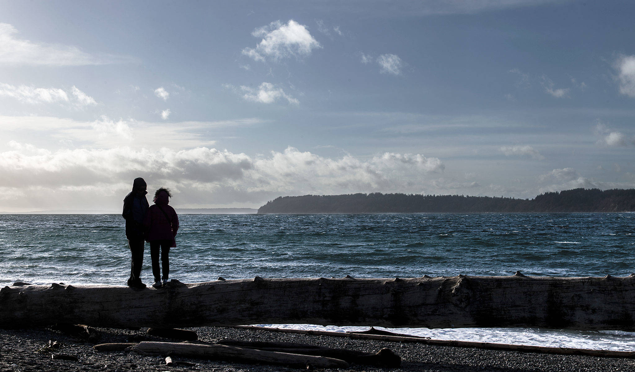 A couple stands on driftwood at Mukilteo Lighthouse Park in January 2018 in Mukilteo. Visitors uncertain about how to pronounce Mukilteo or other locations in Snohomish County, can fall back on Seattle NorthCountry. (Olivia Vanni / Herald file photo)