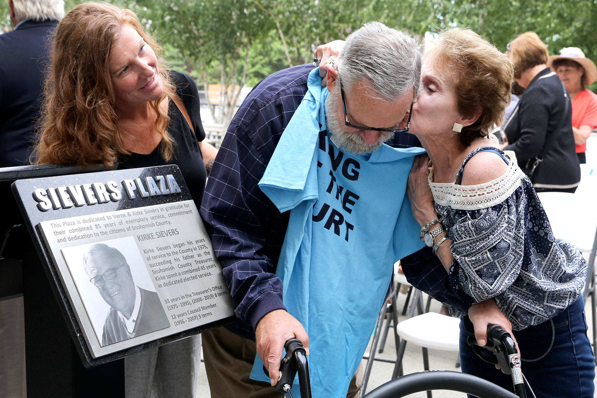 Kirke Sievers (center) gets a kiss from Gerri Donner with Danielle Garton (left) after the dedication of the The Sievers Plaza in Everett on Tuesday. (Kevin Clark / The Herald)