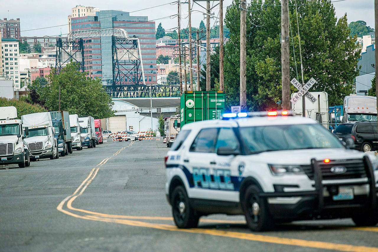 A police officer guards the front of a road block near the Northwest Detention Center in Tacoma on Saturday. A man armed with a rifle threw incendiary devices at an immigration jail in Washington state early Saturday morning, then was found dead after four police officers arrived and opened fire, authorities said. (Rebekah Welch/The Seattle Times via AP)