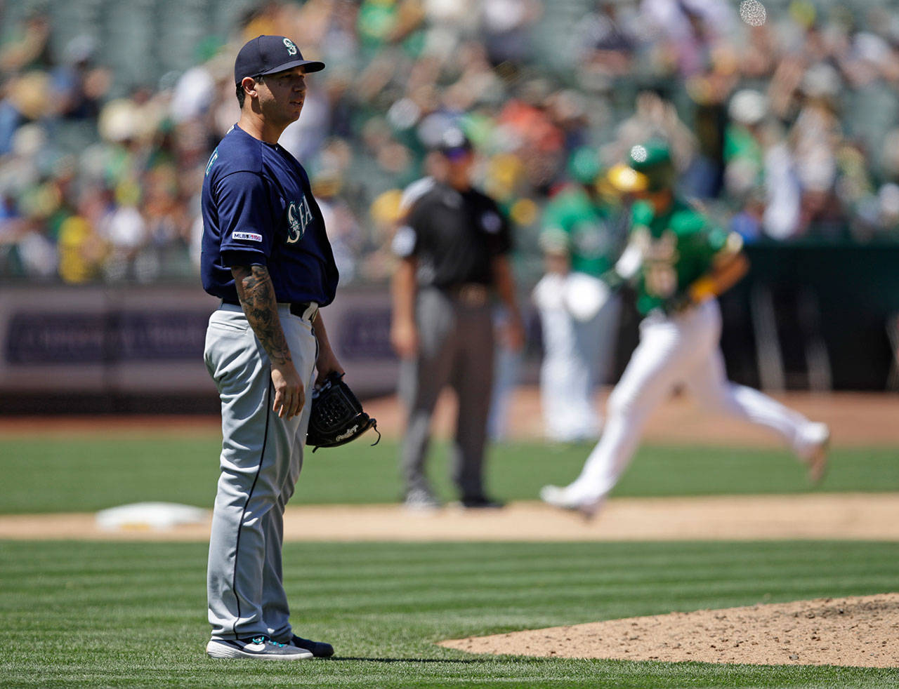 Mariners pitcher Tommy Milone (left) waits for the Athletics’ Chad Pinder (rear) to run the bases after Pinder homered in the sixth inning of a game on July 17, 2019, in Oakland, Calif. (AP Photo/Ben Margot)
