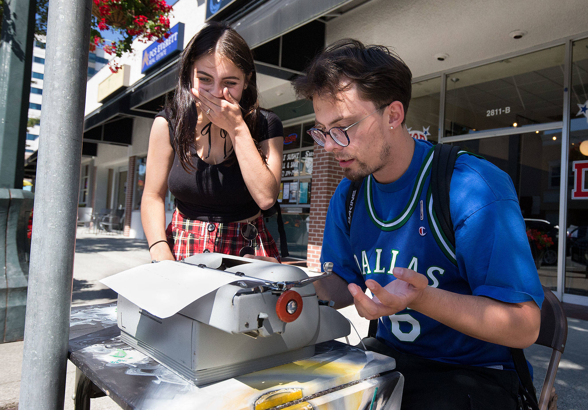 Destiny Miner, 20, reacts as William Mobley, 22, tries to make an apostrophe but gets the number 8 while trying to type on a manual typewriter on Colby Avenue in Everett as part of the city’s annual Word on the Street interactive art project. Neither had used a manual typewriter before sitting down to type. (Andy Bronson / The Herald)