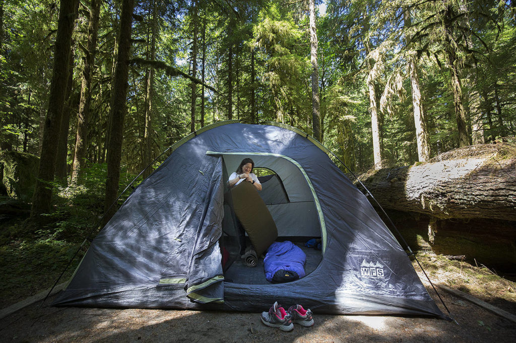 Tracey Silla of Everett leaves her shoes outside as she sets up sleeping bags and pads in her tent at Gold Basin Campground on Friday. (Andy Bronson / The Herald)
