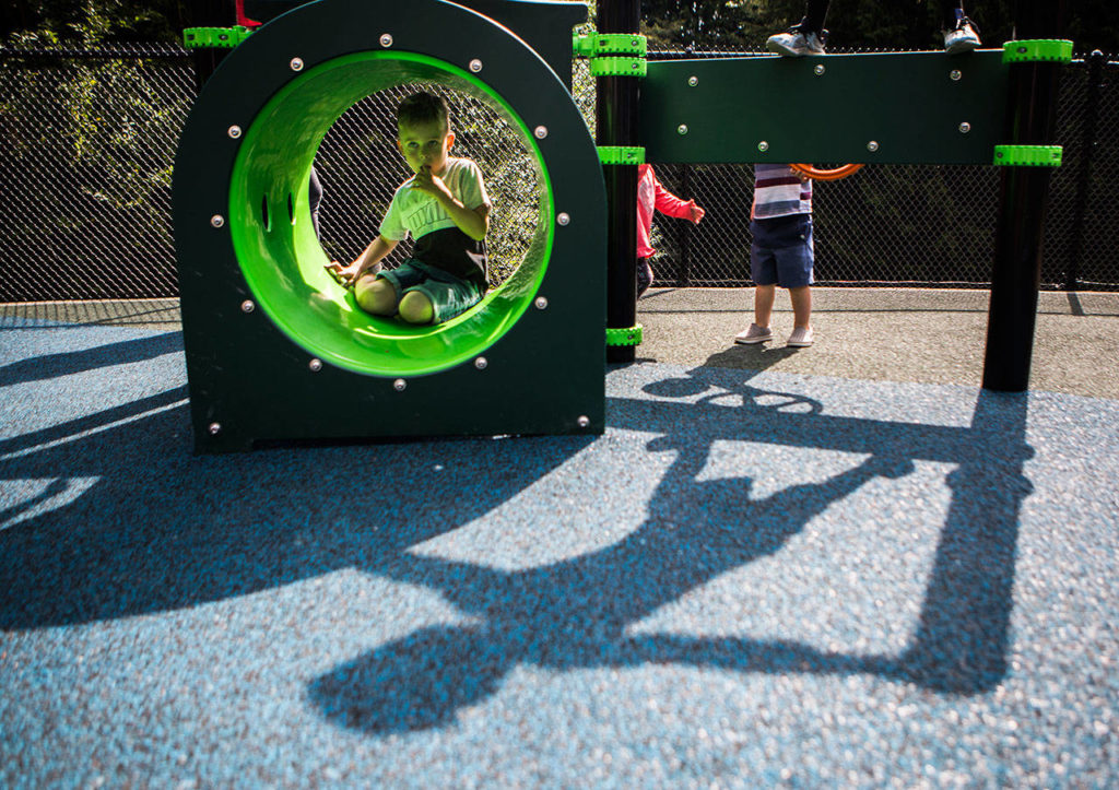 Children climb atop and through one of the new inclusive-style playground structures at the re-opening of Seaview Park’s playground Wednesday in Edmonds. (Olivia Vanni / The Herald)

