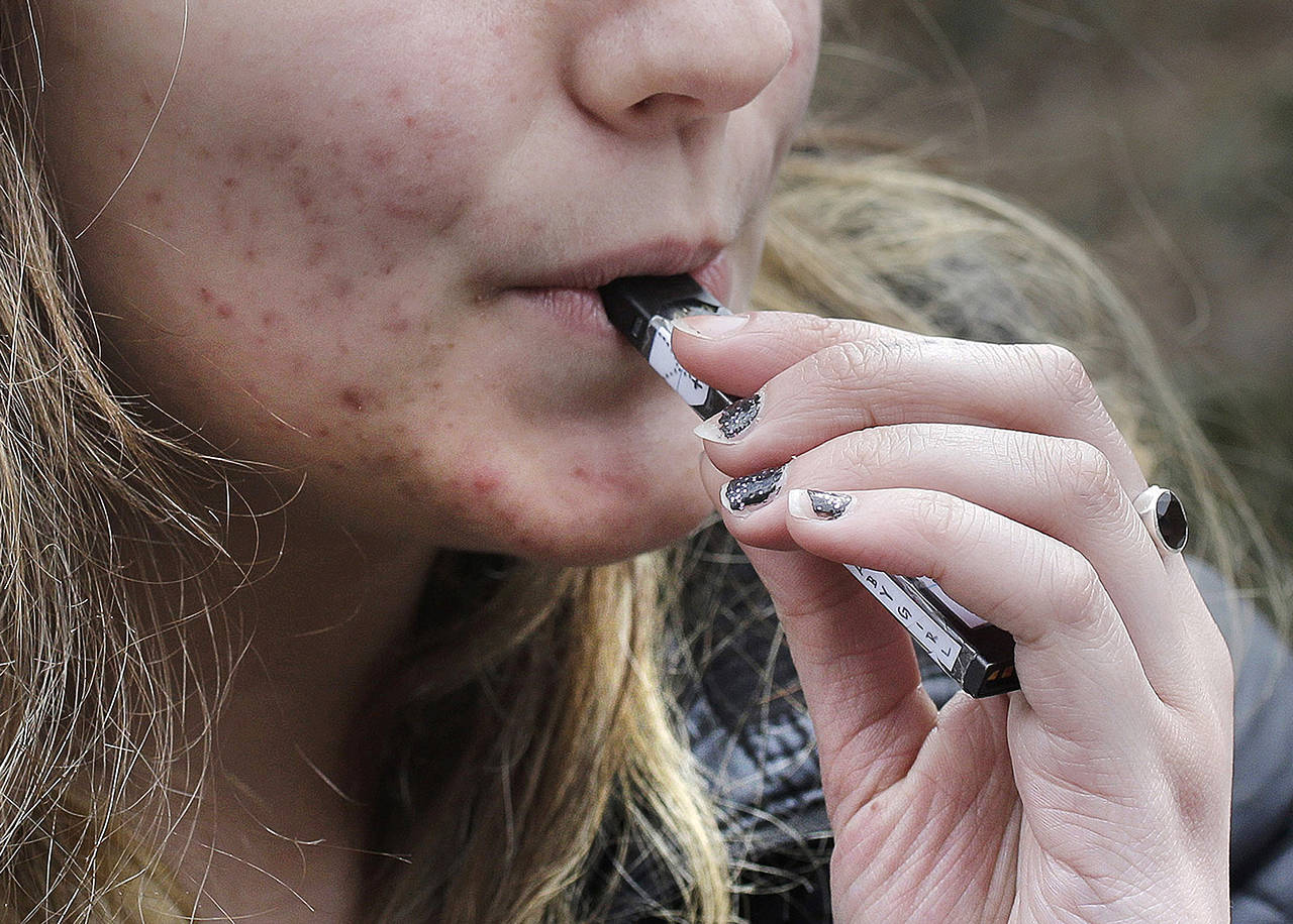 A high school student uses a vaping device near a school campus in Cambridge, Massachusetts in April 2018. (Steven Senne / Associated Press file photo)