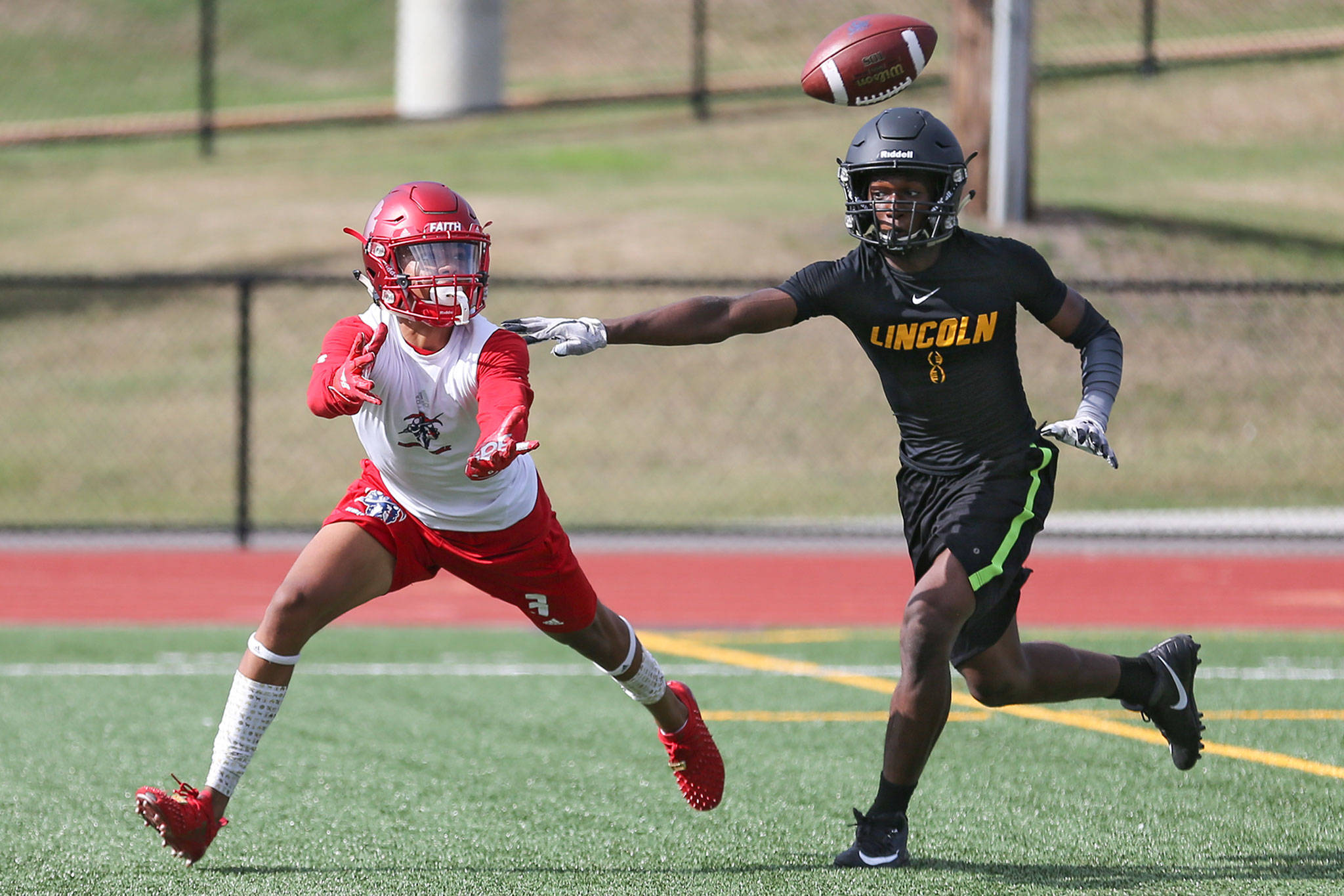 Kennedy Catholic’s Reed Shumpert (left) attempts a catch with Lincoln’s Marian Culpepper trailing during the 12th annual Cougar Championship Passing Tournament on Saturday at Lakewood High School in Arlington. (Kevin Clark / The Herald)