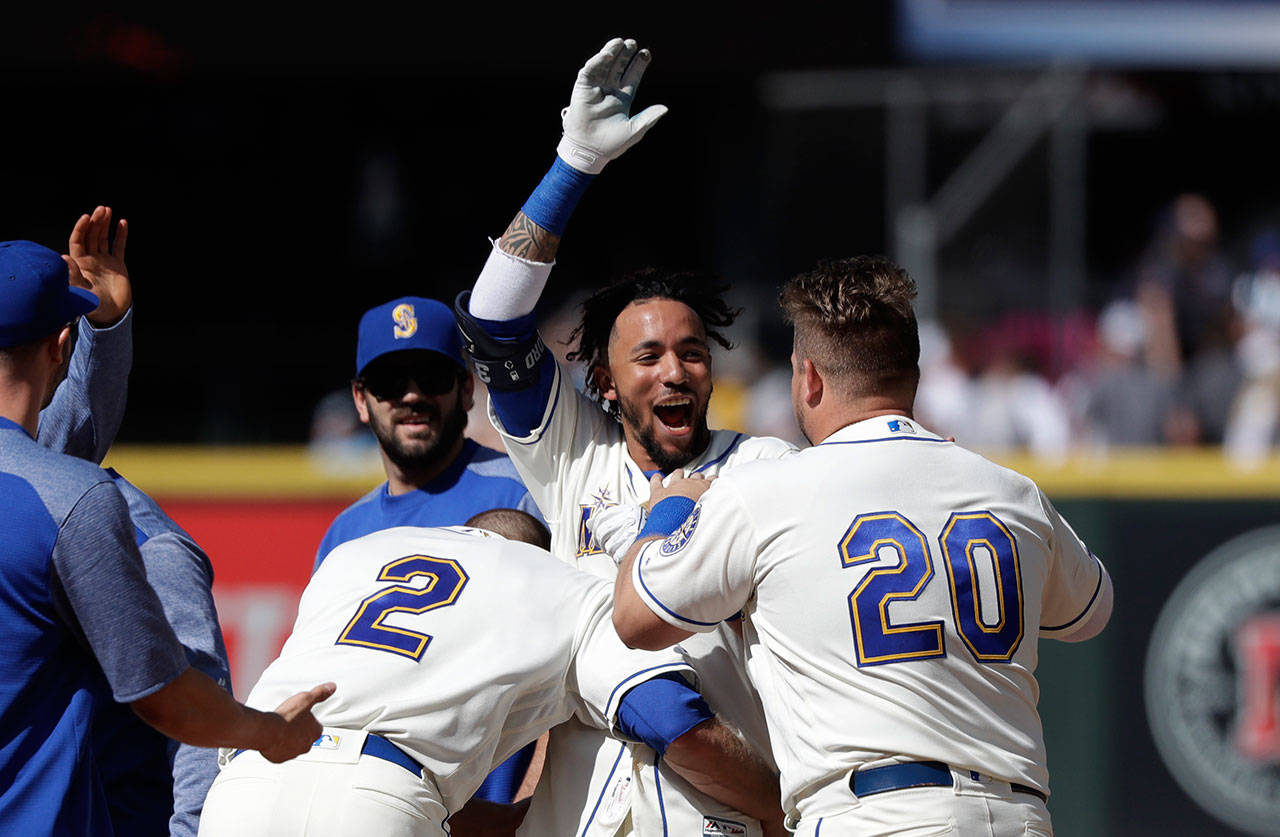 The Mariners’ J.P. Crawford (center) smiles as he is mobbed by teammates after hitting a walk-off single in the 10th inning against the Tigers on July 28, 2019, in Seattle. (AP Photo/Elaine Thompson)