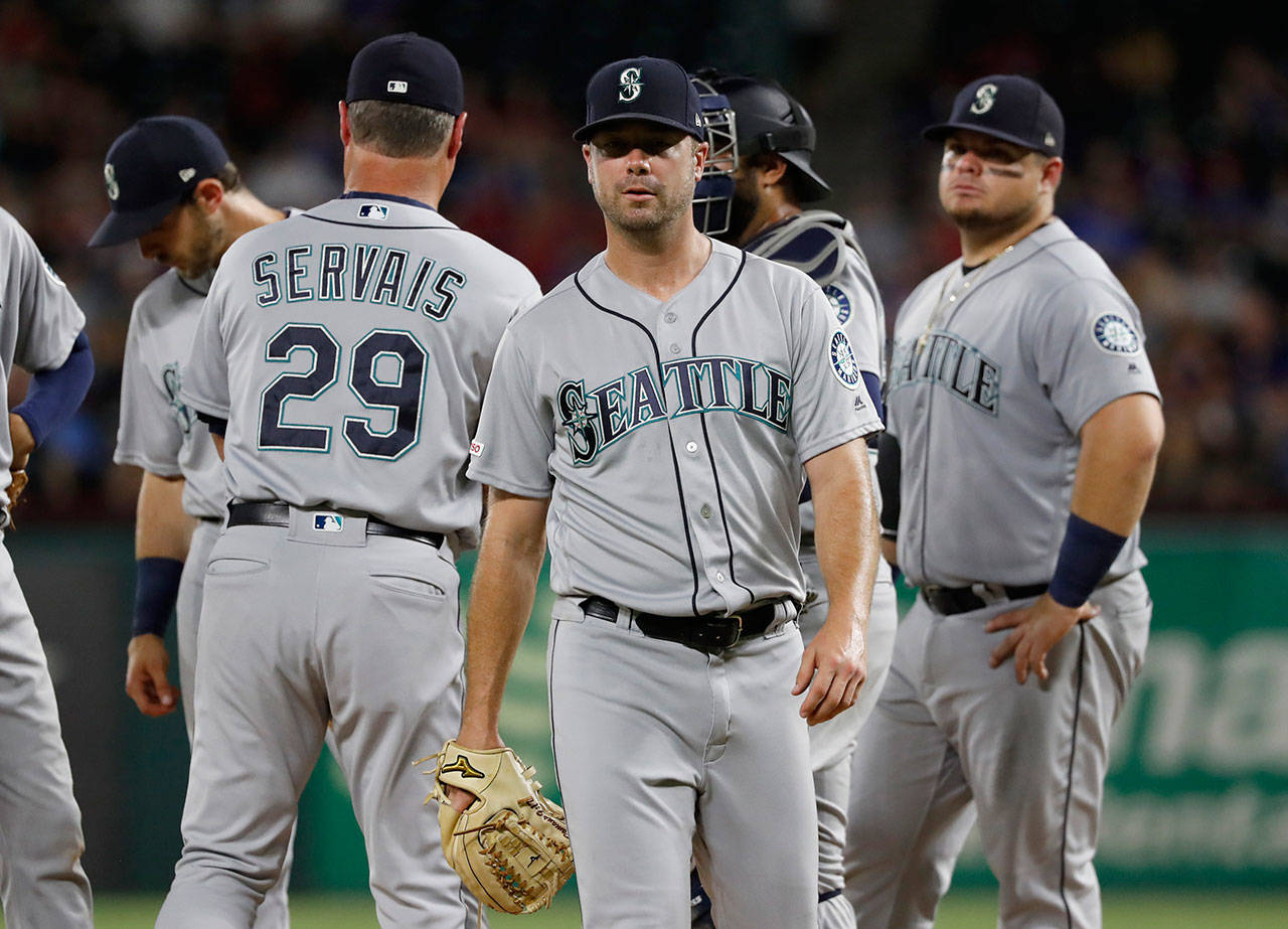 Mariners starter Wade LeBlanc (center) walks to the dugout after turning the ball over to manager Scott Servais (29) during the fifth inning of a game against the Rangers on July 31, 2019, in Arlington, Texas. (AP Photo/Tony Gutierrez)