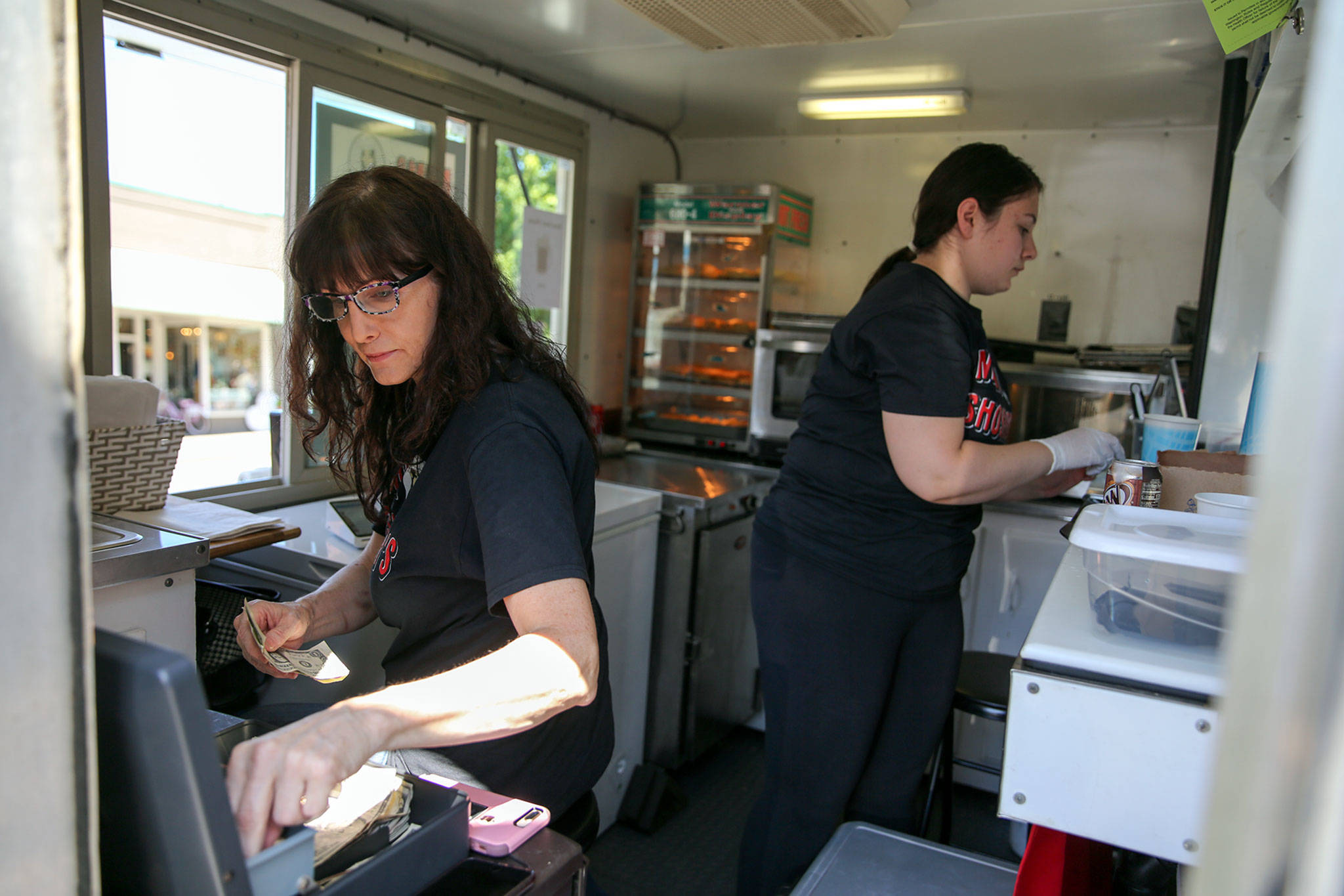 Linda Van Eyck (left) and Shoshana Hazan work in their food truck, Mama Shoshana’s, during Kla-Ha-Yah Days in Snohomish. (Kevin Clark / The Herald)
