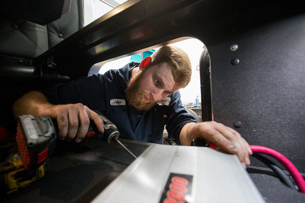 U.S. Marine veteran Jesse Gates installs a power inverter at Motor Trucks, an Everett business that sells and repairs heavy duty trucks. (Andy Bronson / The Herald)
