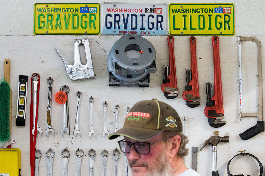 Cliff Edwards in his shop with previous license plates. His current plate on his truck spells out GRAVDGR. (Andy Bronson / The Herald)
