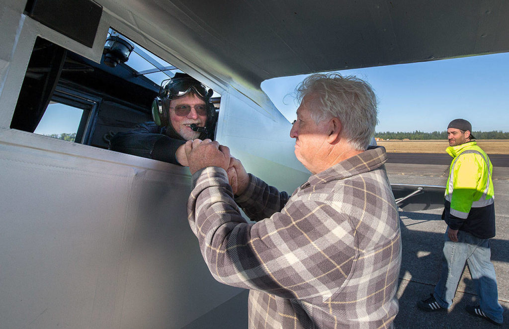 John Norman congratulates pilot Ron Fowler’s hand after he successfully flew Norman’s replica of the Spirit of St. Louis on July 28 in Arlington. (Andy Bronson / The Herald)
