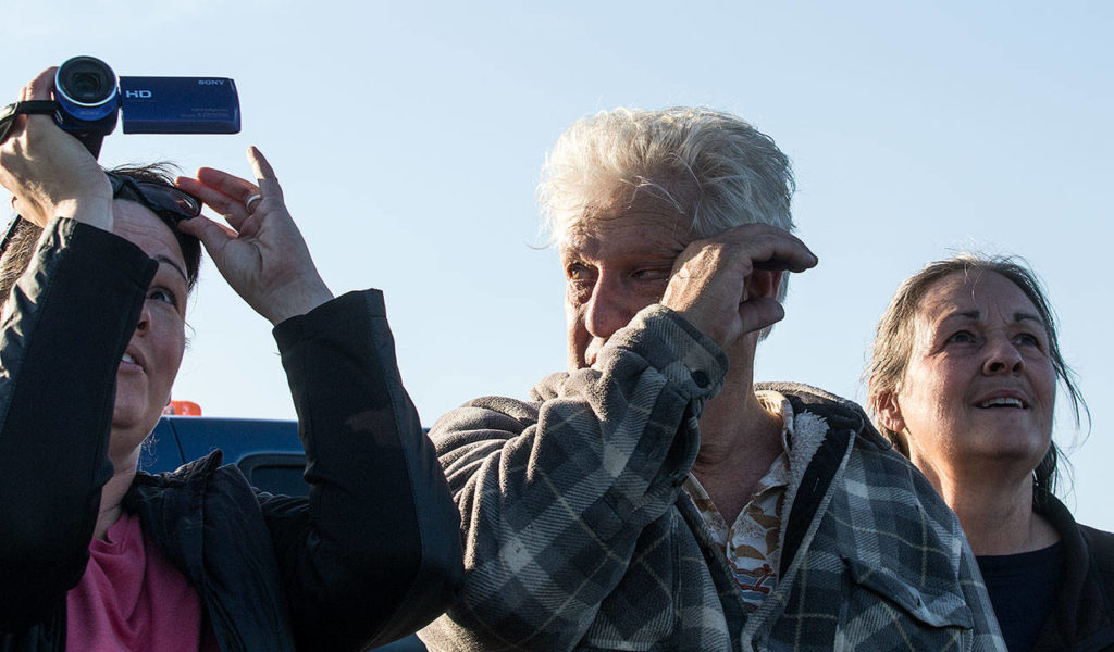 John Norman is overcome with emotion as his replica of the Spirit of St. Louis takes off on its first flight from Arlington Municipal Airport on July 28. His daughter Amber Nelson takes video as his wife, Heather, watches the plane fly ovals around the airfield. (Andy Bronson / The Herald)
