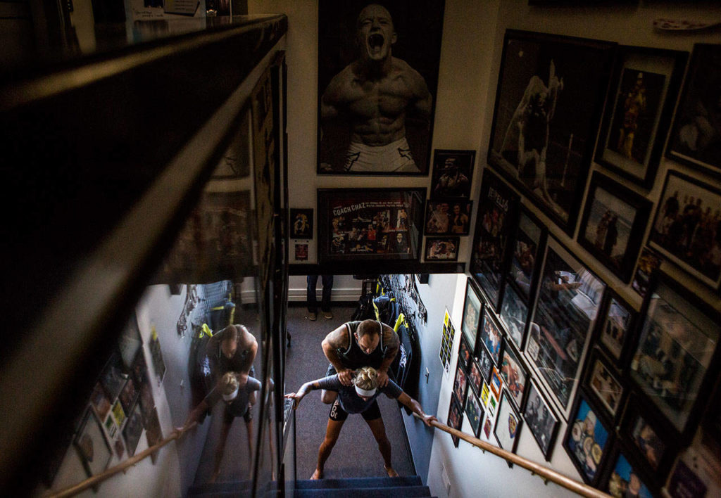 Miranda Granger braces herself at the base of the stairs as Charlie Pearson climbs on her back to be carried during her training at Charlie’s Combat Club on July 26, 2019, in Everett. (Olivia Vanni / The Herald)
