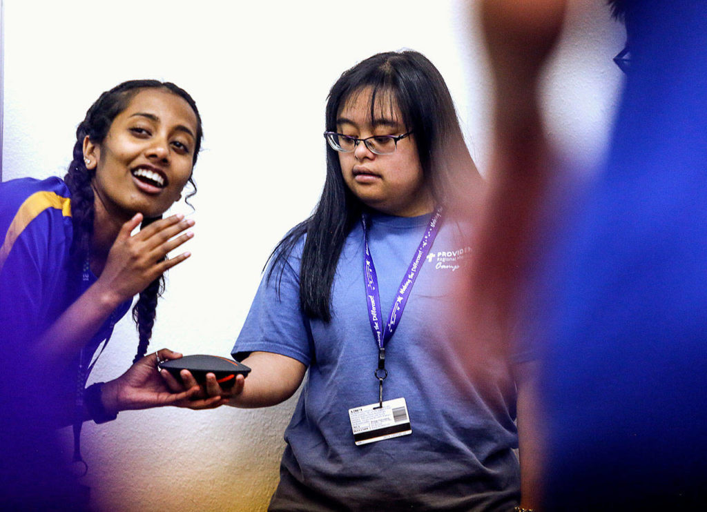 Margot Amalachandran, 21, a unit leader at Camp Prov, helps Bre Baylon with a speaker that blasts camp songs during activity time in Lions Hall at Forest Park on Wednesday. (Dan Bates / The Herald)
