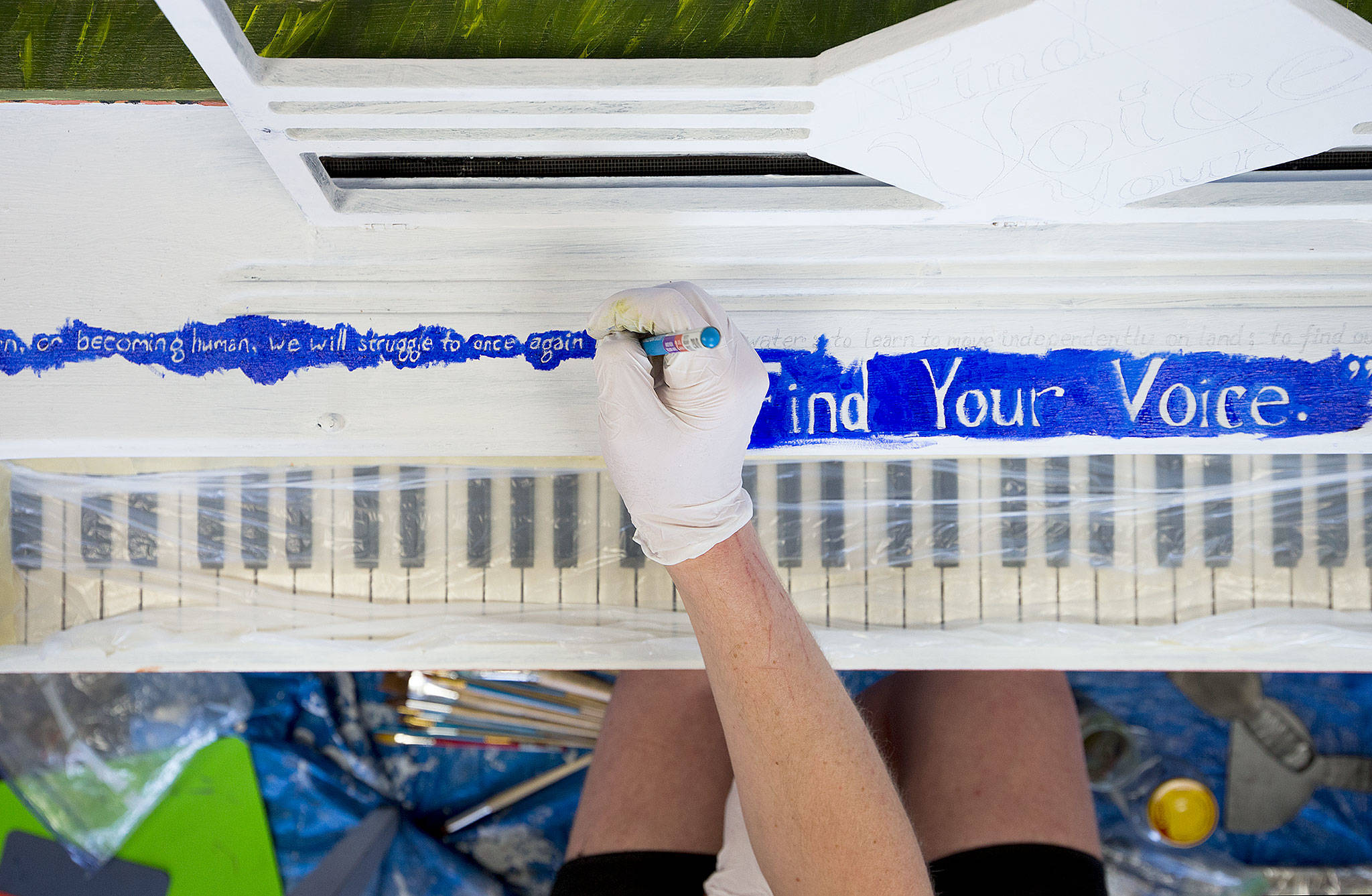 Artist Nicoli Dominn outlines a personal quote on a piano. Dominn is painting the newest piano addition to Everett’s annual Street Tunes, a Greek interpretation of “The Little Mermaid.” (Andy Bronson / The Herald)