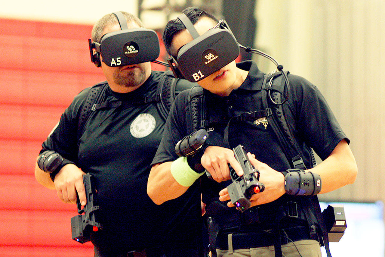 In virtual reality, Department of Corrections Officer Mike Woodruff (left) and Snohomish County deputy Tim Leo walk down a hallway during a training session in Lynnwood on Wednesday. (Zachariah Bryan / The Herald)