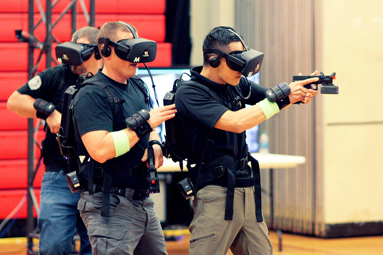 Department of Corrections Officer Mike Woodruff (from left), Snohomish County deputy Lucas Robinson and deputy Tim Leo carefully enter a virtual reality room during training in Lynnwood on Wednesday. (Zachariah Bryan / The Herald)