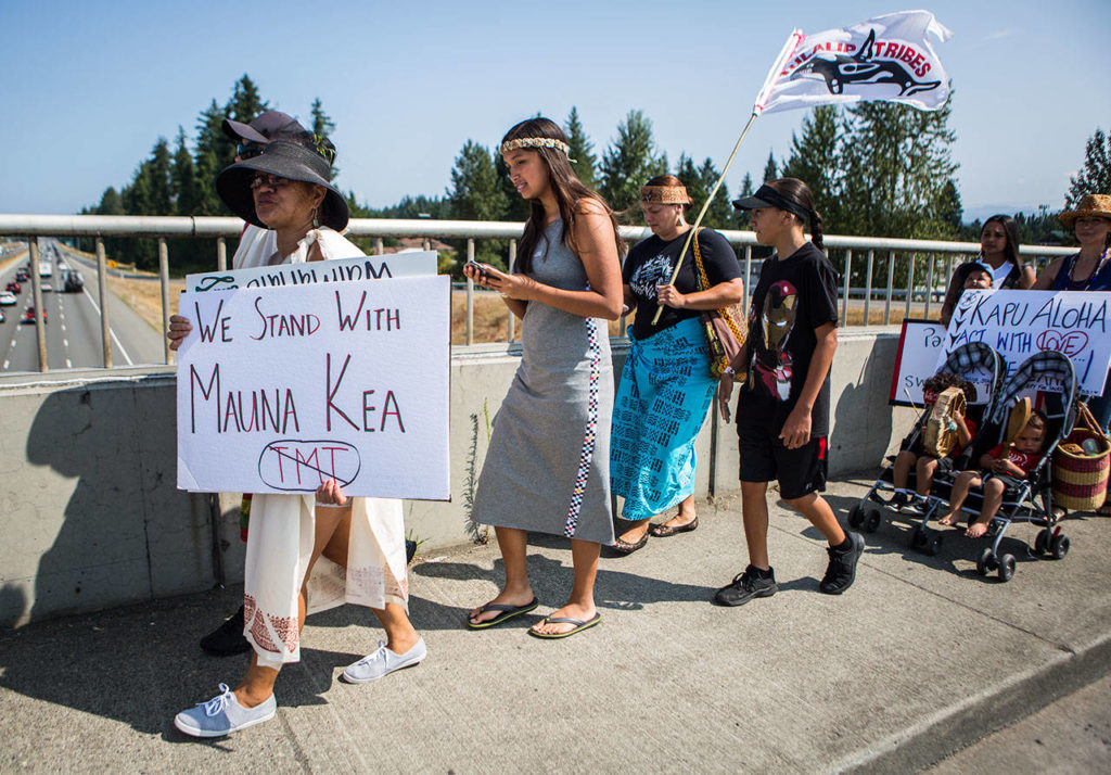 People make their way across the I-5 overpass singing, chanting and carrying signs and flags Saturday in Marysville. (Olivia Vanni / The Herald)
