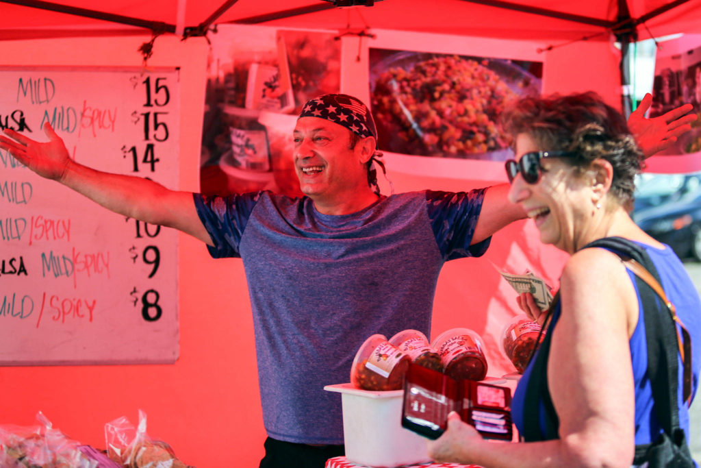 Bubba of Bubba’s Salsa greets the new location with Peggy Webb (right) Sunday morning at Everett Farmers Market in Everett. (Kevin Clark / The Herald)
