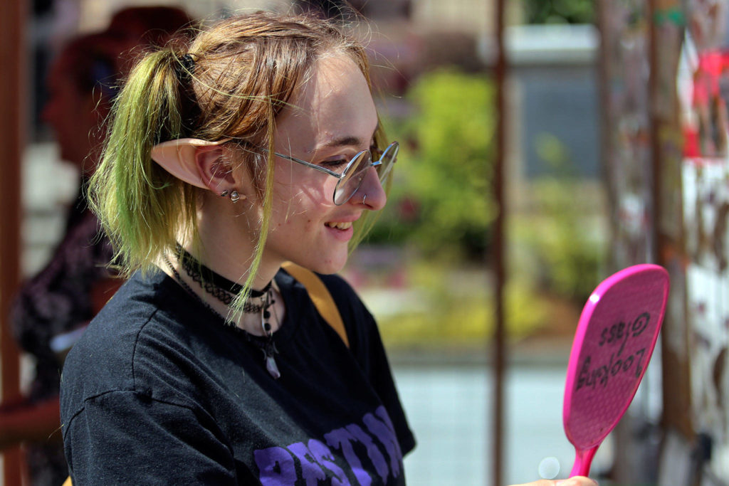 Bailey Frisbie looks over custom elf ears at one of the 130 or so booths Sunday morning at Everett Farmers Market in downtown Everett. (Kevin Clark / The Herald) 
