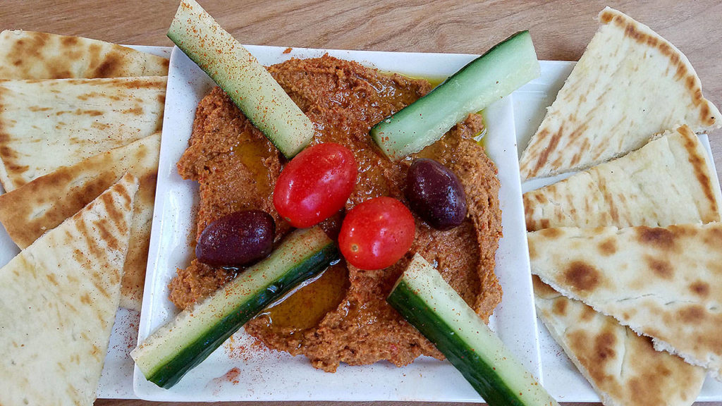 The muhummara plate is a spread of roasted red pepper with walnuts, pomegranates, onions and cayenne pepper, served with tomato, cucumber, olive and pita bread. (Sharon Salyer / The Herald)
