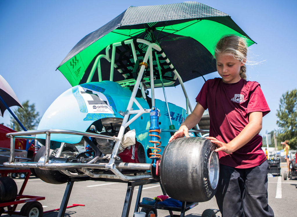Lily Jo Decker, 8, checks the tires on her car before her race at the Washington Quarter Midgets Association’s Wild Wild West race on Aug. 4 in Monroe. (Olivia Vanni / The Herald)
