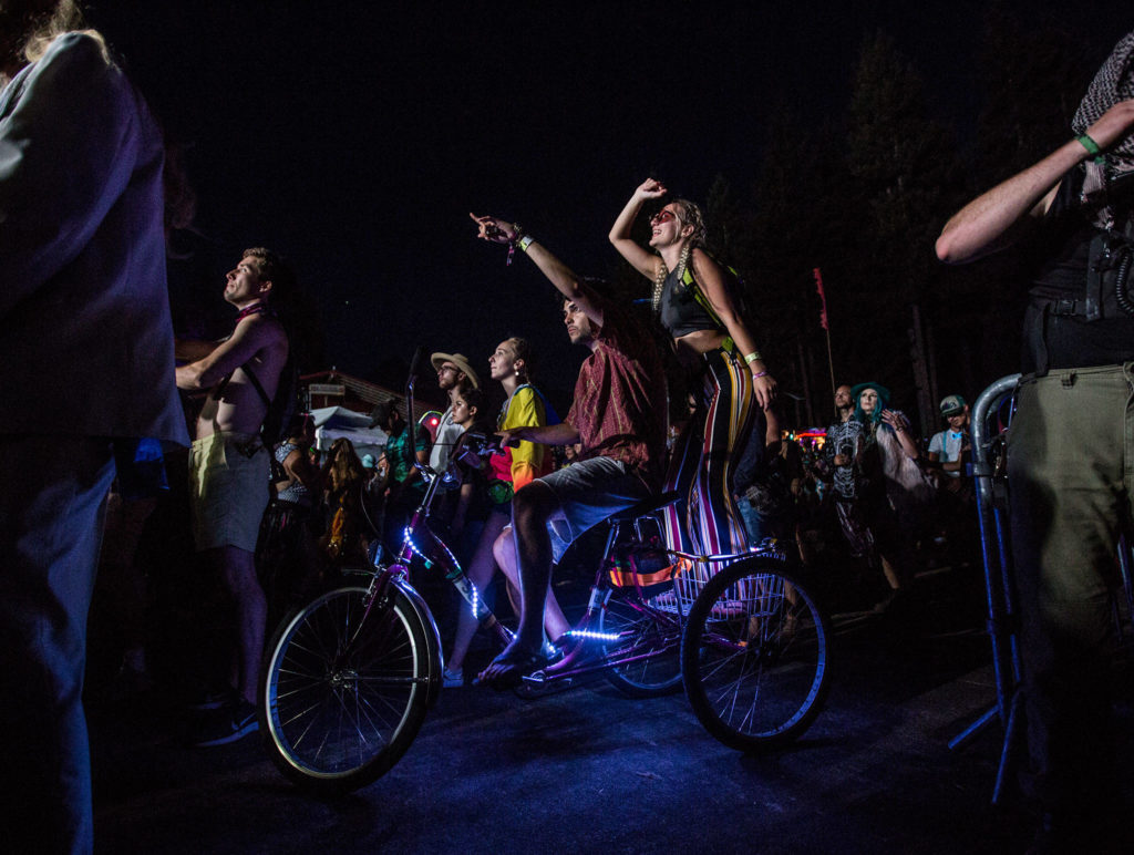 People dance on a bike in the crowd during G Jones’ performance on the final day of Summer Meltdown on Sunday, Aug. 4, 2019 in Darrington, Wash. (Olivia Vanni / The Herald)