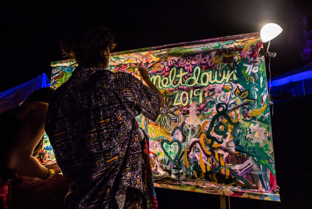 People add to the communal Meltdown painting during the third day of Summer Meltdown on Sunday, Aug. 4, 2019 in Darrington, Wash. (Olivia Vanni / The Herald)