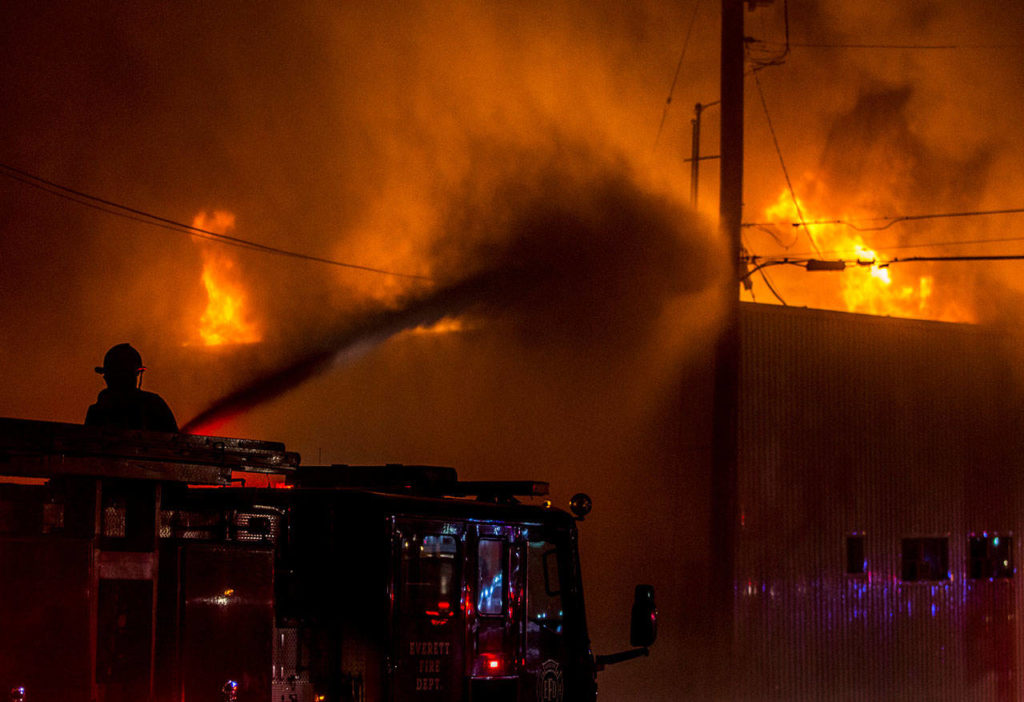 A Everett firefighter sprays water on the Judd & Black appliance store that burned on Sept. 21, 2018 in Everett. (Olivia Vanni / Herald file)
