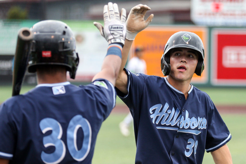Hillsboros Corbin Carroll (right) gets a high-five from Hops teammate Eddie Hernandez after scoring a run during Hillsboros 10-1 win over the AquaSox on Sunday at Funko Field in Everett. (Kevin Clark / The Herald)
