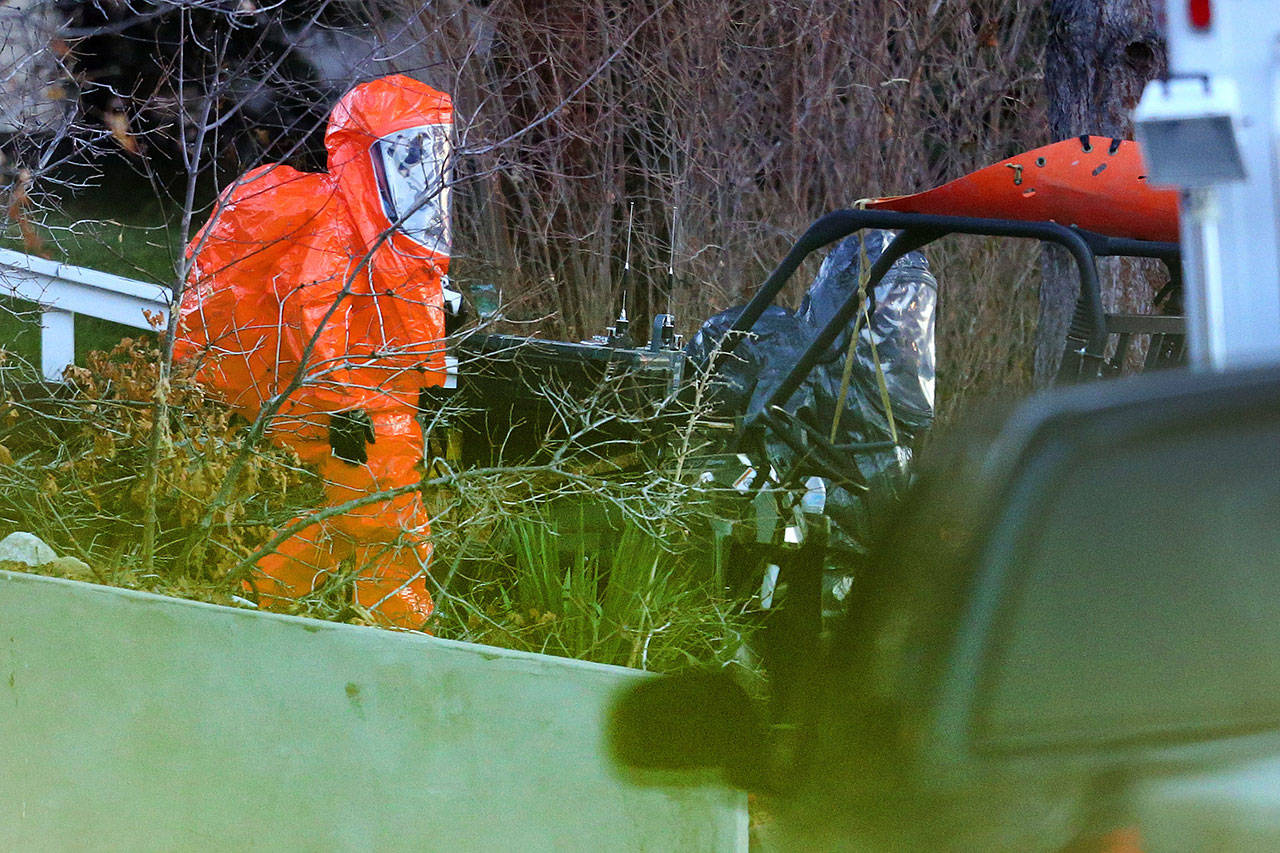 Two men in protective suits exit a residence as local and federal law enforcement agencies respond to a drug bust in Cottonwood Heights, Utah, on Nov. 22, 2016. The raid on Aaron Shamo’s home in the upscale suburb of Cottonwood Heights, agents found a still-running pill press in the basement, thousands of pills and more than $1 million in cash stuffed in garbage bags, according to court documents. (Scott G Winterton/The Deseret News via AP)