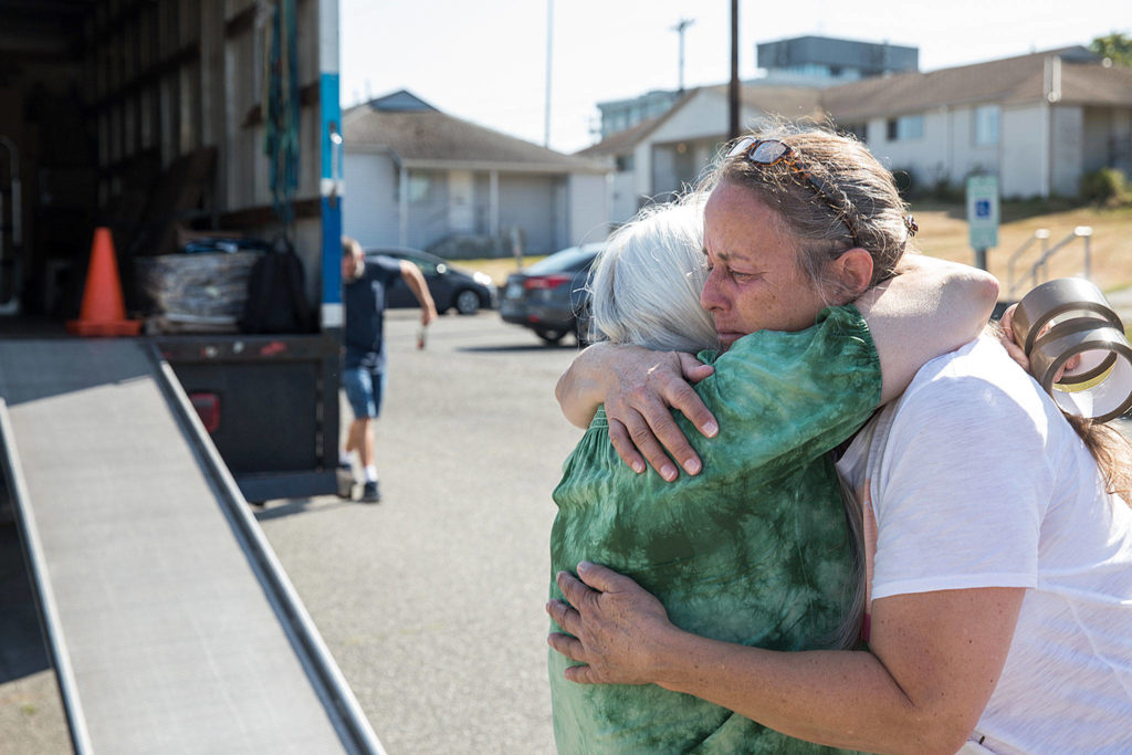 Longtime friends Beverly Bowers and Kathleen Mullen (right) hug as movers load up boxes into a truck. (Lizz Giordano / The Herald)
