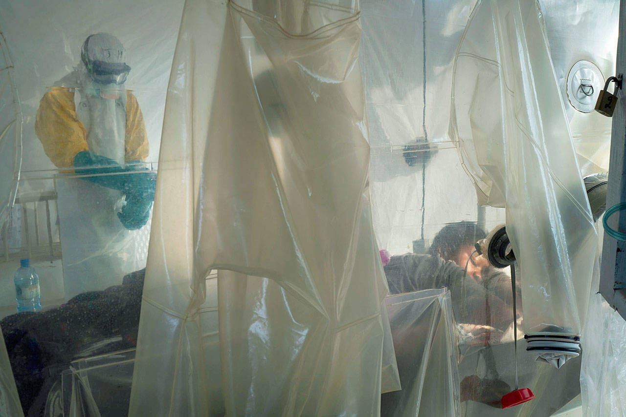 Health workers wearing protective gear check on a patient isolated in a plastic cube at an Ebola treatment center in Beni, Congo, on July 13. Health authorities in Congo have halted an Ebola treatment study early with good news: Two of the four experimental drugs seem to be saving lives. More than 1,800 people have died in the African country’s yearlong outbreak. (AP Photo/Jerome Delay, File)