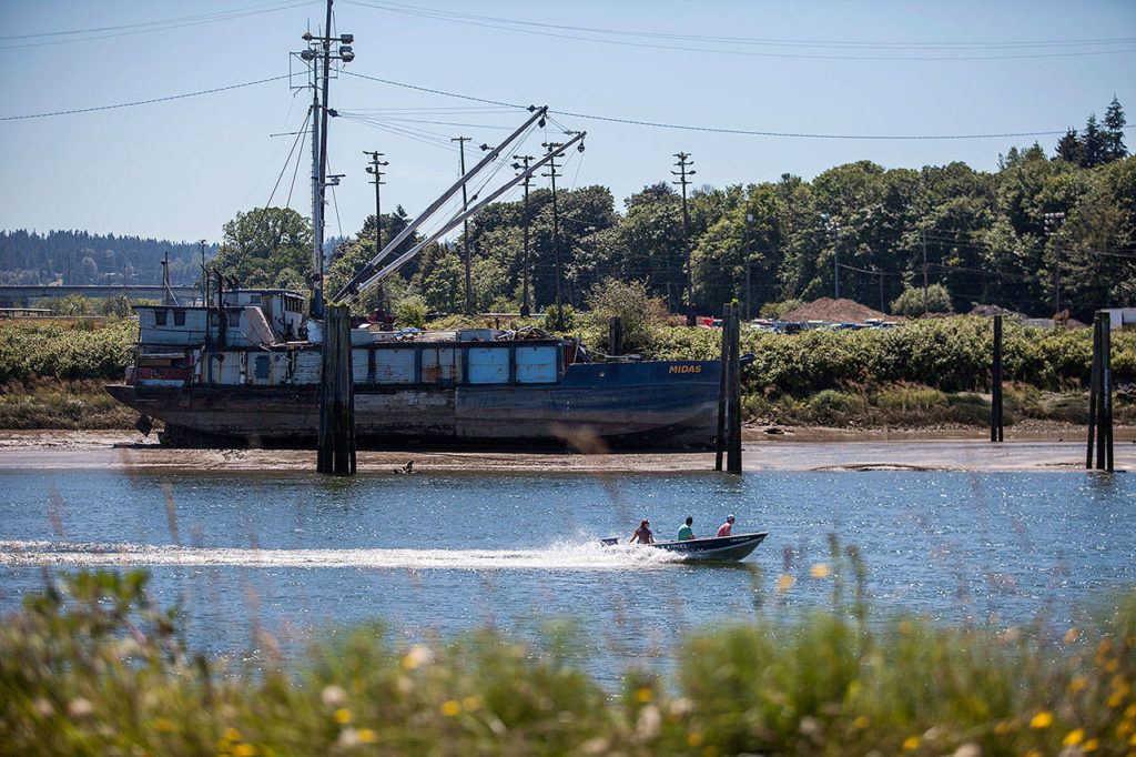 A boat drives past the Hannah Marie along the bank of the Snohomish River on July 3, 2018, in Everett. (Olivia Vanni / Herald file)

