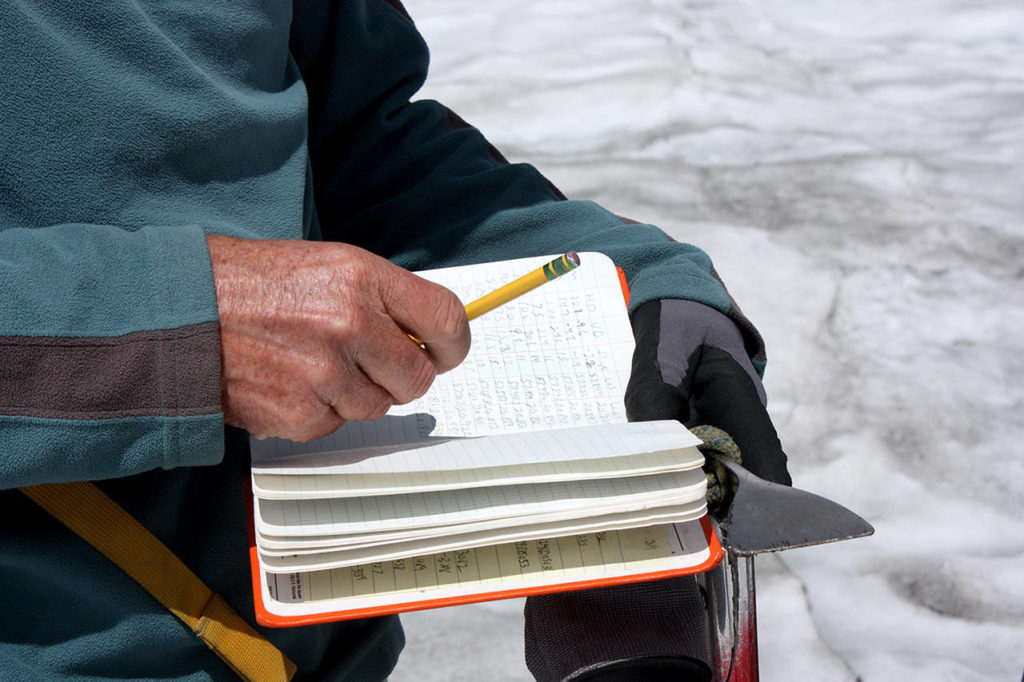 Mauri Pelto records his measurements of the shrinking Columbia Glacier in a notebook. This year may prove to be one of the worst yet when it comes to melting. (Zachariah Bryan / The Herald)
