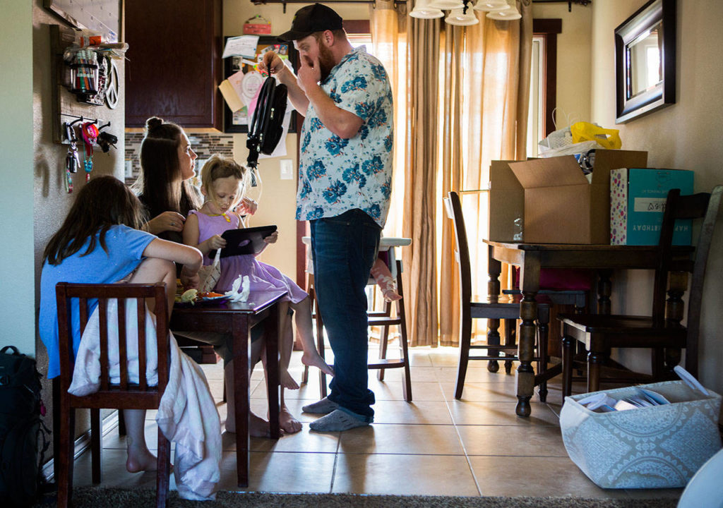 Sadie Sheldon sits on her mother Erin Sheldon’s lap, and her father, Kellen Sheldon, helps adjust her feeding-tube backpack while the family eats lunch. (Olivia Vanni / The Herald)
