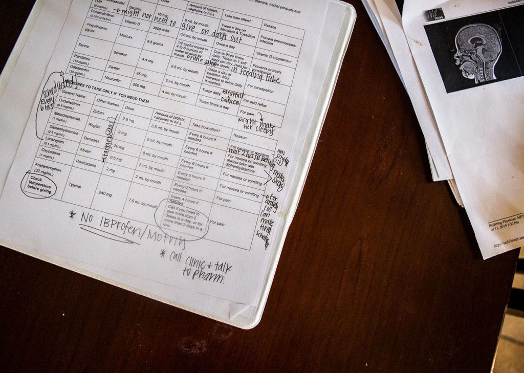A list of medicines, times to administer them and handwritten notes cover a binder filled with Sadie’s medical information. (Olivia Vanni / The Herald)
