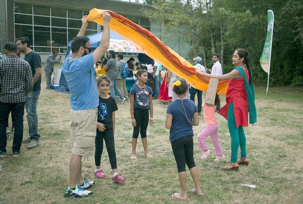 Kids run under a sash as it’s folded at the second annual UTSAV Mela festival. (Julia-Grace Sanders / The Herald)
