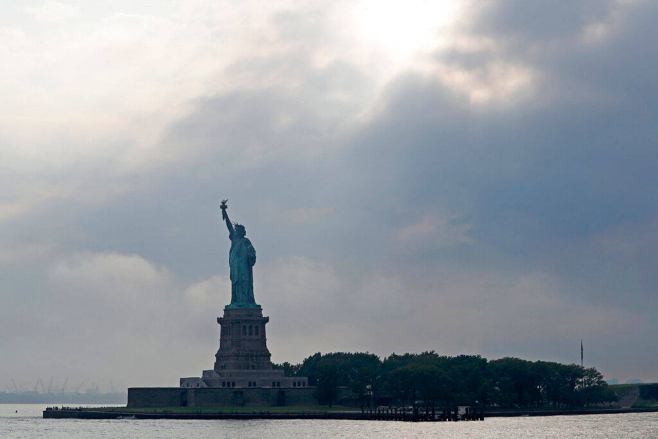 Clouds gather over the Statue of Liberty, Aug. 14, in New York. A plaque inside the statue’s pedestal displaying Emma Lazarus 1883 poem “The Colossus,” best known for its line about welcoming “your tired, your poor, your huddled masses yearning to breathe free,” was aluded to Tuesday when acting Director of Citizenship and Immigration Services Ken Cuccinelli suggested in an NPR interview that the line should be changed to “give me your tired and your poor who can stand on their own two feet and who will not become a public charge.” (Kathy Willens / Associated Press)